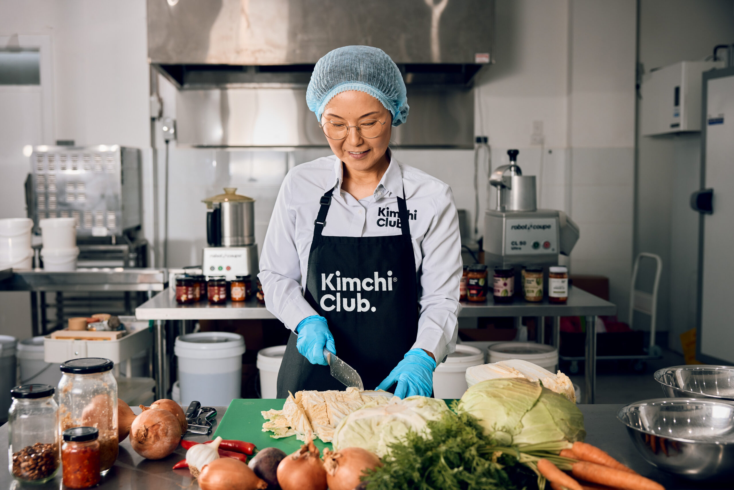 Minka Park standing in an industrial kitchen cutting produce at a bench
